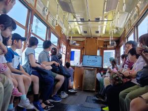 電車内で水道局職員が紙芝居を読み聞かせている画像