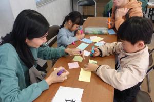 付箋にメッセージを書く家族の写真